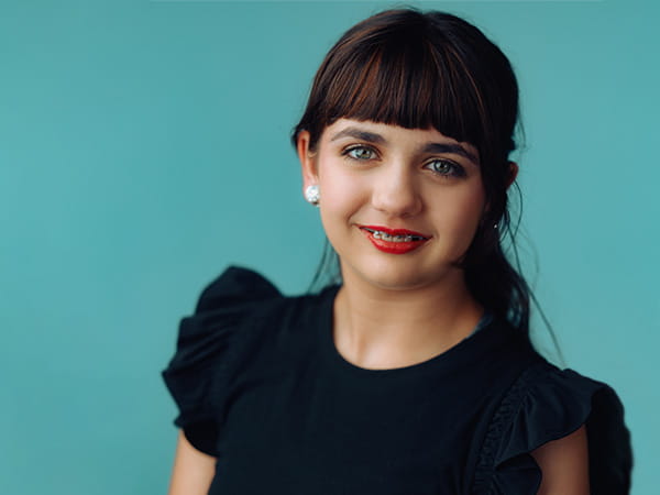 A professional headshot of Makenzie Childs on a turquoise background.