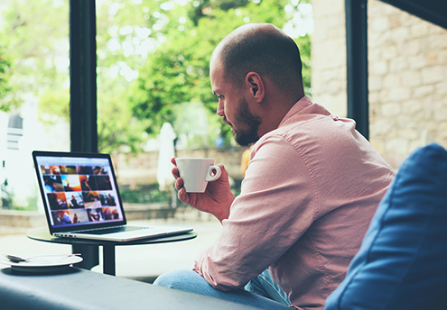 man drinking coffee looking at a laptop screen