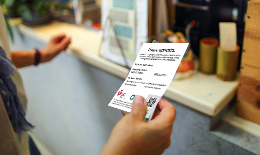 A person is holding their aphasia ID card in their hand to show at a retail counter.
