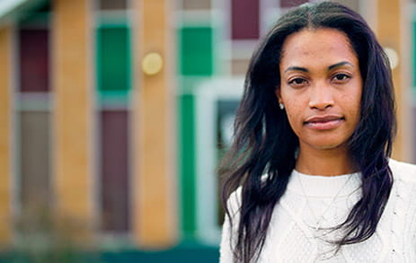 Stroke survivor, Chelsea, is outside standing in front of a colorful building.