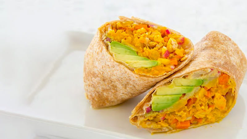 A tuna wrap with avocado is sliced in half and arranged on a plate.