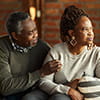 A displeased Black mature woman is ignoring her husband who is talking to her in the living room.