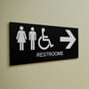 A sign showing female, male, and wheelchair icons with an arrow pointing to restrooms
