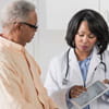 A doctor is showing information on a tablet to her senior male patient.
