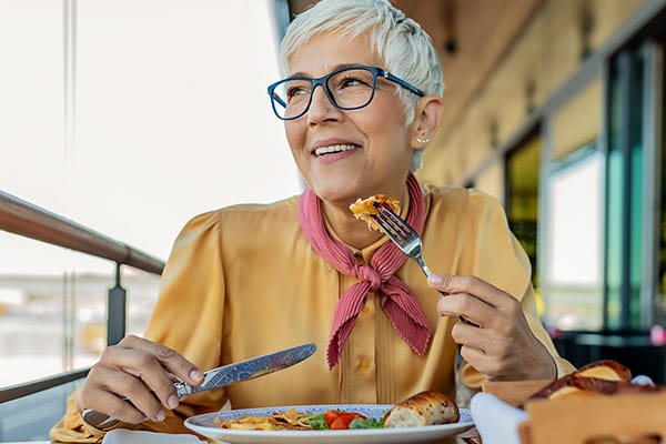 Una mujer mayor sonríe mientras come una comida balanceada.